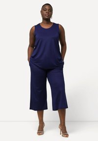 Námořnická modrá bezrukávová halenka s kulatým výstřihem a kapsami, doplněná širokými culottes. Hladká tkanina s volným střihem a minimalistickým designem.