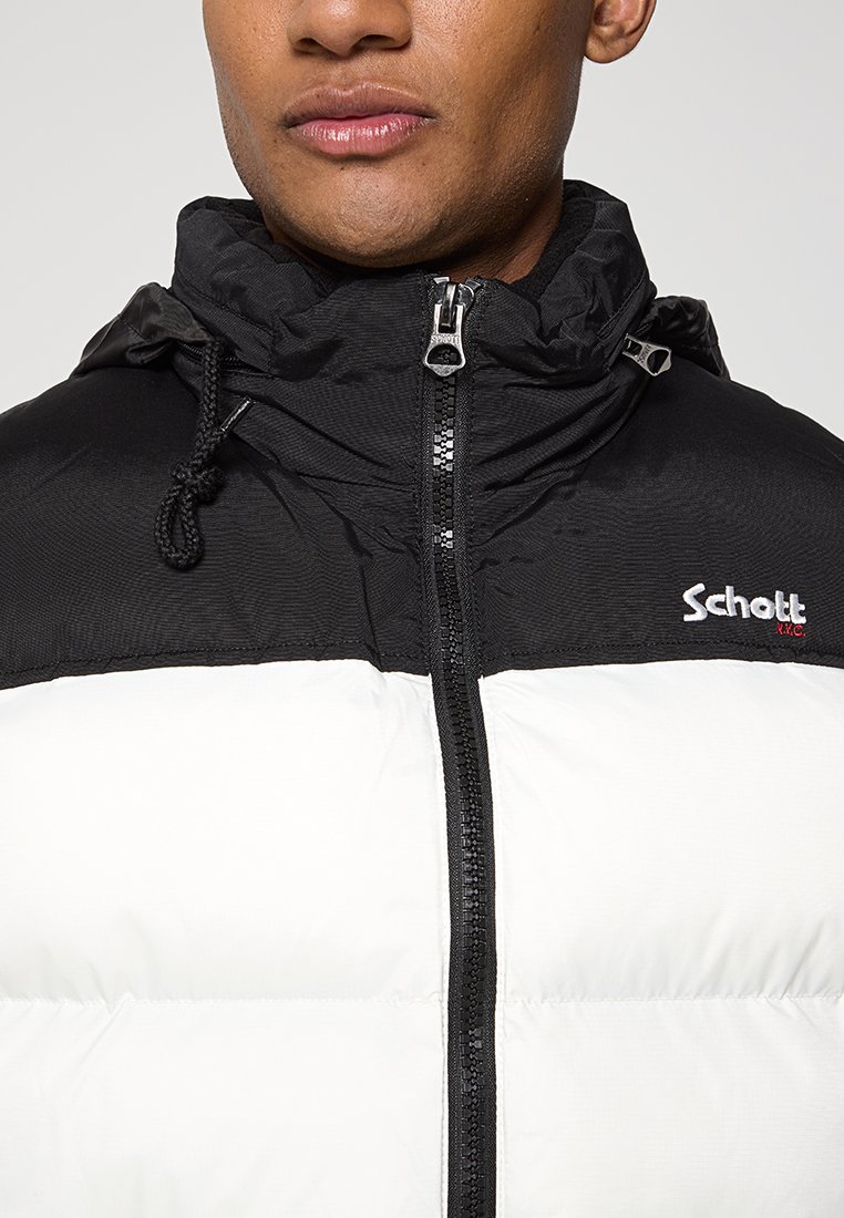 Doudoune noire et blanche avec zip à l'avant, capuche à cordon de serrage et logo brodé. Texture douce avec un design bicolore et des panneaux cousus.