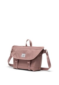 Borsa a tracolla in tessuto rosa con pattina, patch logo frontale, tracolla regolabile e due chiusure a fibbia frontali. Zip sulla parte superiore.