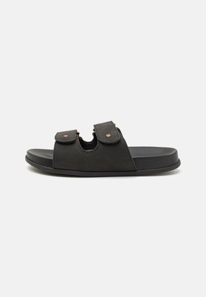 Black slide sandals with two adjustable straps, subtle copper rivets, and a flat sole. Made from synthetic material for durability and comfort.