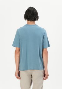 Tricou cu mânecă scurtă, cu o croială lejeră, din bumbac de culoare albastru deschis. Guler simplu, de tip crew și textură netedă, fără logo-uri sau aplicații vizibile.