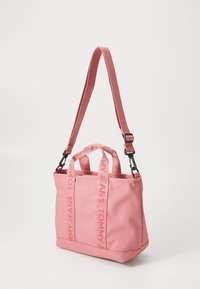 Lichtroze totebag met dubbele handvatten en een verstelbare schouderriem. Bevat patroonbranding op de handvatten en een stevig ontwerp van stof.