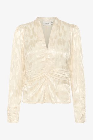 Blouse crème avec des manches longues, un décolleté en V profond et des détails froncés à la taille. Le tissu a une texture subtilement brillante.