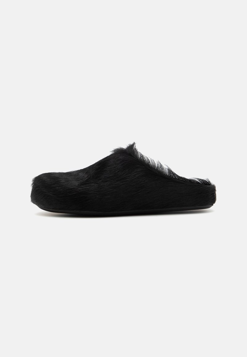 Black fur-lined slipper with a rounded toe and a low back. Features a soft, textured upper and a flat sole. No visible hardware.