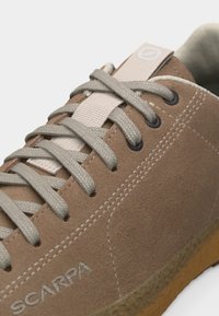 Ταν δερμάτινο αθλητικό παπούτσι από σουέντ με γκρι κορδόνια, λευκό ράψιμο, με την επωνυμία "SCARPA" στο πλάι και σόλα από καουτσούκ σε χρώμα τσίχλας.