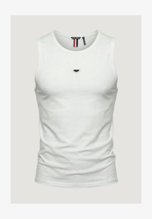 Camiseta de tirantes blanca hecha de algodón, con un escote redondo y un pequeño detalle de logo negro en el pecho. Textura suave.