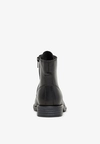Schwarze Lederstiefeletten mit glatter Oberfläche, Reißverschluss und niedrigem, gestapeltem Absatz. Verfügt über ein dezentes Nahtdetail auf der Rückseite.