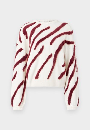 Biely pletený sveter s dlhými rukávmi, zdobený diagonálnymi huňatými tmavými červenými pruhmi na tele a rukávoch.