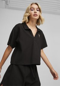 Polo shirt nero testurizzato con colletto a contrasto e maniche corte, caratterizzato da un logo discreto sul petto e abbinato a pantaloni corti coordinati.