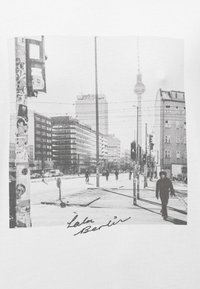 Μαύρο-λευκό γραφικό σε λευκό πουκάμισο που απεικονίζει μια σκηνή δρόμου στο Βερολίνο, με κτίρια, φωτεινούς σηματοδότες και πεζούς.