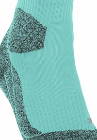 Türkise Socken mit schwarzen gemusterten Abschnitten, die ein strukturiertes Design und ein Logo an der Seite präsentieren.