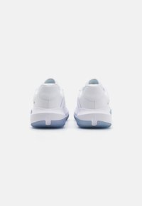 Baskets blanches avec une tige en cuir lisse, un col rembourré et des accents bleu clair sur la semelle. Forme arrondie avec une adhérence texturée sur la semelle extérieure.