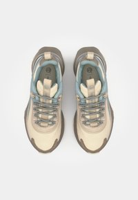 Beige og grå atletiske sko med blå detaljer, teksturert overdel og runde snører. Har en polstret krage og en distinkt gummisåle.