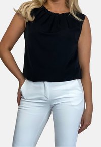 Mustat hihattomat ylhäätopit, joissa on laskostettu kaula-aukko, yhdistetty valkoisiin kapeisiin housuihin, luoden kontrastisen värikombinaation. Sileä kankaan rakenne.