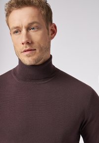 Dunkelvioletter Rollkragenpullover aus feinem Strickmaterial, mit einer taillierten Passform und geripptem Kragen, der eine glatte Textur aufweist.