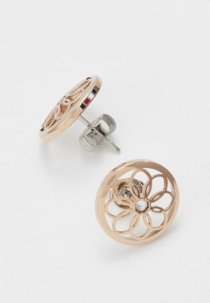 Ronde oorknopjes van roségoud met een bloemmotief als uitsnede en een centrale heldere edelsteen, de ene toont de voorkant en de andere de zijkant met een driedelig kleurdetail.