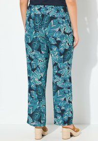 Pantalons ample à motif de feuilles bleues sur fond marine, dotés d'une taille élastique et d'une texture de tissu léger.