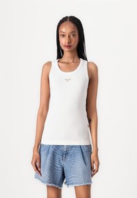 Hvit ribbet tanktop med et sentralt "JOOP!" logo, kombinert med blå denimshorts som har et gjentatt tekstmønster og slitt kant.