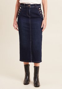 Gonna midi in denim scuro con dettagli in lacing laterale, tasche frontali e taglio dritto. Presenta accessori in bronzo e cuciture a contrasto.