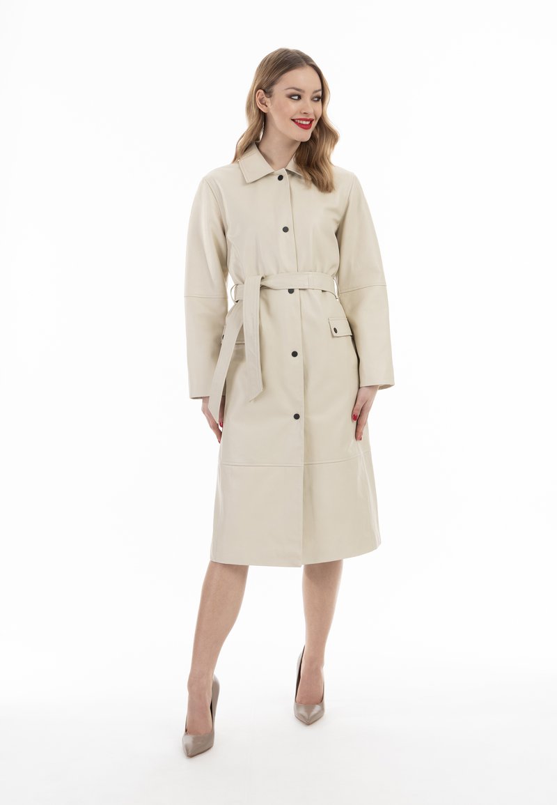 Beige leren jas met een ceintuur in de taille, knoopsluiting, lange mouwen en twee zijzakken. Gladde textuur, knielang ontwerp.