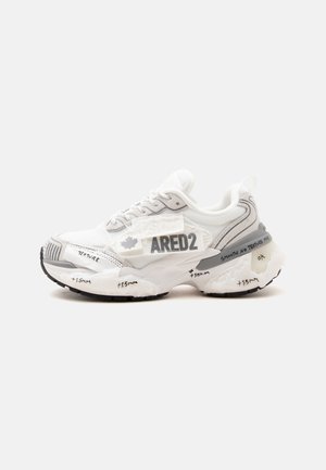 Hvid og grå sneaker med tyk sål, sort tekst og symboler på sålen og siden, og "ARED2" trykt på ydersiden.