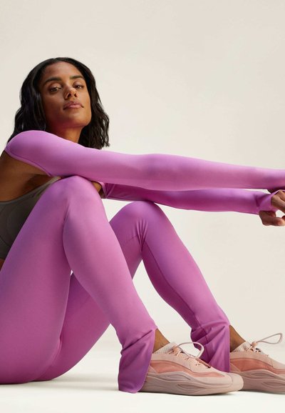 Tajta lila leggins med långa ärmar, tillverkade av ett mjukt tyg. Kombinerat med ljusrosa sneakers med mjuk textur och unik design.