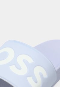 Ανοιχτό μωβ σανδάλι slide με φαρδιά λουρί που έχει λευκό λογότυπο. Μαλακή, ματ υφή με ανθεκτικό πέλμα προσαρμοσμένο για άνεση.