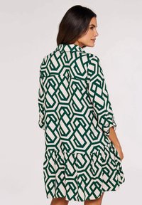 Grünes und weißes gemustertes Kleid mit geometrischem Design, Schmucksaum, langen Ärmeln und Kragen.