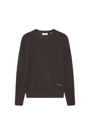 Dark brown knitted sweater with a round neck, textured pattern, ribbed cuffs and hem, featuring small white embroidered text on the bottom.