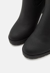 Stivaletti neri alla caviglia con finitura testurizzata, punta arrotondata e tacco leggermente rialzato. Presentano cuciture rinforzate e suola in gomma resistente.