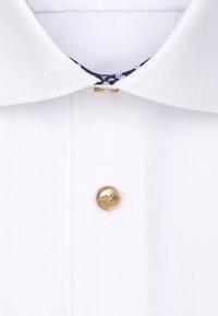 Colletto di una camicia bianca con un interno a fantasia. Chiusura centrale con un unico bottone dorato. Tessuto liscio con dettagli di cucitura visibili.