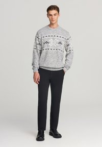 Maglione grigio e bianco a motivo con collo tondo e maniche lunghe; abbinato a pantaloni neri e stivali neri chunky. Design semplice e moderno.