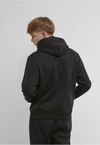 Black hoodie made of soft fabric, featuring a large hood, ribbed cuffs, and a kangaroo pocket, with a smooth texture.