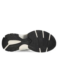 Černobílá podrážka atletické boty se strukturou z gumy, vzorovaným profilem pro lepší přilnavost a výrazným detailem loga.
