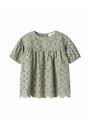 Lichtgroene blouse met korte pofmouwen, geborduurd bloemmotief, geschulpt zoom en een ronde halslijn. Eyelet stofstructuur.