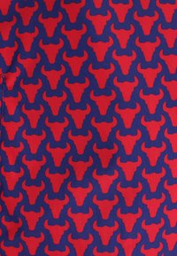 Geweven stof met een herhalend patroon van rode stierkoppen op een donkerblauwe achtergrond. Textuurafwerking met zichtbare weving.