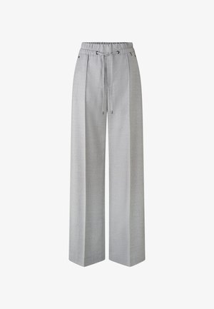 Pantalons larges gris clair avec une taille élastique et un cordon de serrage. Le tissu présente une texture subtile, avec des poches latérales et des accents métalliques.