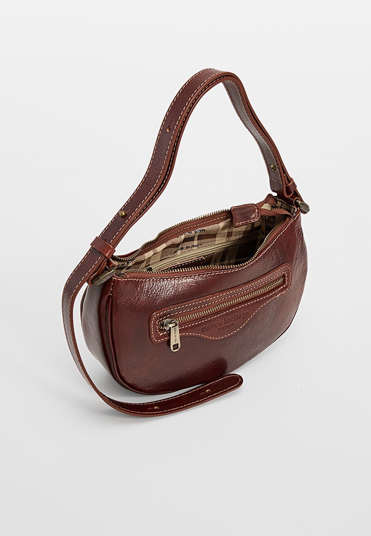 Brązowa skórzana torba na ramię z przednią kieszonką na zamek, regulowanym paskiem i częściowo otwartym zamkiem u góry, pokazującym beżowe wzorzyste wnętrze.