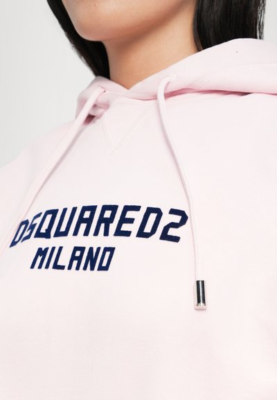 Roosa kapuutsiga särk, millel on nöör, esiküljel on tumesinise värvi tekst "DSQUARED2 MILANO." Pehme kangas, nähtavad õmblusdetailid ja metalline nööriotsik.
