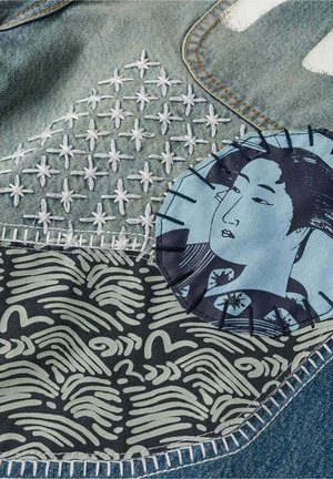 Tessuto in denim con stelle bianche ricamate, una toppa con motivo astratto in bianco e nero e una toppa circolare cucita con il volto di una donna.