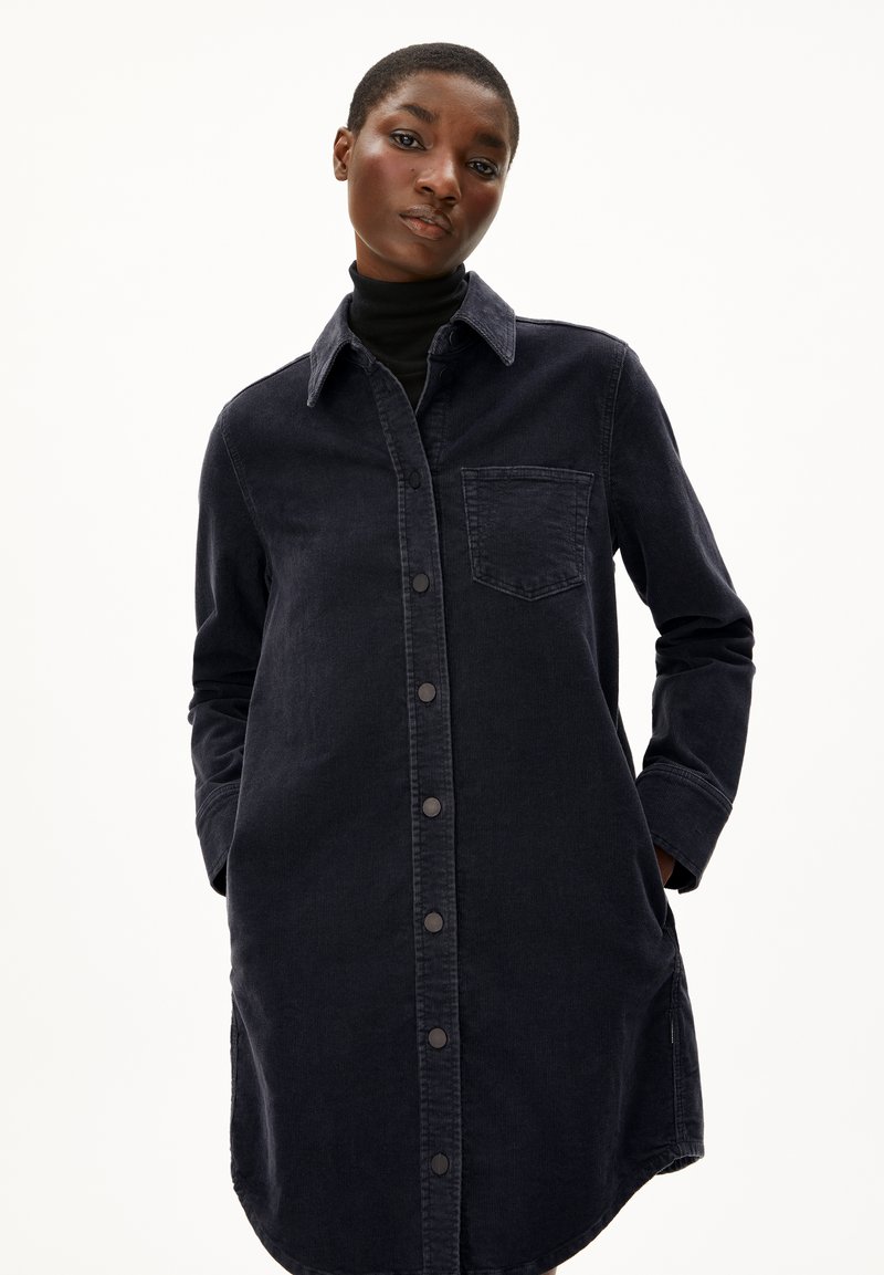 Dunkelblaues Denimhemdkleid mit langen Ärmeln, durchgehender Knopfleiste und Brusttasche. Es hat einen Kragen und einen leicht abgerundeten Saum.