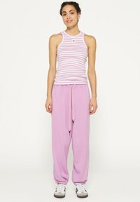 Lichtroze gestreepte tanktop gecombineerd met losse, effen roze sweatpants met een verstelbare trekkoord en elastische cuffs.