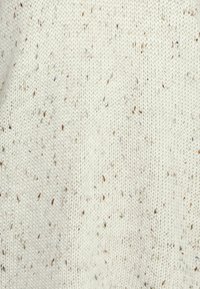 Tecido de malha em tom creme com um padrão texturizado, apresentando manchas dispersas de castanho e verde por todo o lado. Textura suave da lã.