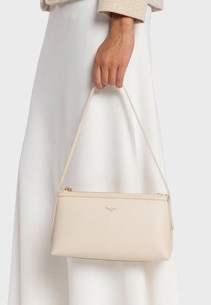 Sac à main beige zippé au design fin, en matière texturée, avec une bandoulière et un petit logo embossé à l'avant.