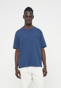 Μπλε ναυτικό βαμβακερό t-shirt με στρογγυλή λαιμόκοψη και κοντά μανίκια. Διαθέτει μικρό λογότυπο στο αριστερό στήθος. Μαλακή, άνετη εφαρμογή.