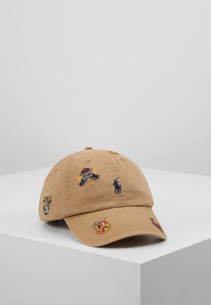 Casquette de baseball beige avec logos et blasons Polo multicolores brodés, présentée sur un piédestal blanc sur fond gris clair.