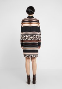 Long-sleeve dress featuring horizontal stripes in brown, beige, and black, with a leopard print band at the hem. Back zip closure visible.