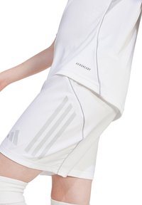 Weißes Sporthemd und Shorts mit glatter Textur, versehen mit grauen Streifen und dem Etikett "AEROREADY" auf dem Hemd.