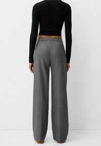 Grijze wijde broek van stof met verticale streepmotieven, voorzien van een soepele tailleband en een relaxte fit. Het materiaal lijkt zacht en op maat gemaakt.