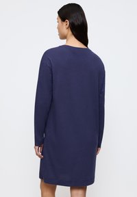 Abito maglione blu navy con maniche lunghe, scollo rotondo e tessuto testurizzato. Fessure laterali e minimo dettaglio di cucitura sul retro.